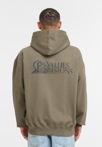 Olivgrön hoodie tillverkad av mjukt tyg, med en stor grafisk design på ryggen, ribbade muddar och en huva med dragsko.