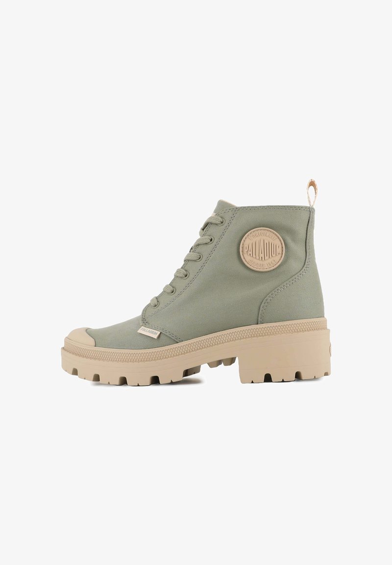 Botte haute vert olive avec embout en caoutchouc beige et semelle épaisse. Comprend un patch logo rond, une tige en textile, un laçage à l'avant et une languette de traction.