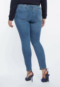 Blå jeans i denim med slim fit, avsmalnande ben, två bakfickor och hög midja. Obs: bärs med marinblå klackar.