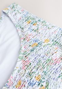 Kvetovaný top so shirringu s bielym vnútrom a textúrovaným povrchom farebných vzorov v ružových, žltých, modrých a zelených odtieňoch.