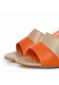 Sandalias de punta abierta con un diseño en bloques de color beige y naranja. Textura de cuero suave con suela plana y tiras anchas.