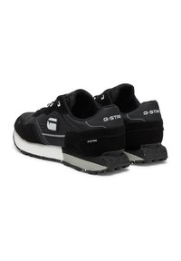 Melni sporta apavi ar ādas un sintētisku materiālu sajaukumu. Aprīkoti ar teksturētu dizainu, baltām un pelēkām uzstrādājumiem un gumijas zolīti.