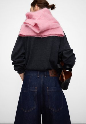 Ciemnoszary, oversize sweter z jasnoróżowym szalem z moheru zarzuconym na ramiona, w połączeniu z ciemnymi, wysokim stanem dżinsami.