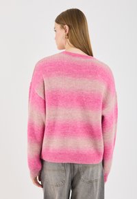 Maglione a righe rosa e crema con vestibilità rilassata, orlo a costine e maniche lunghe. Tessuto morbido, scollo rotondo e spalle cadenti.