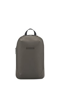 Sac à dos gris foncé en matériau lisse et durable. Dispose d'une poignée supérieure et d'un compartiment principal zippé, avec des accents subtils et un design minimaliste.