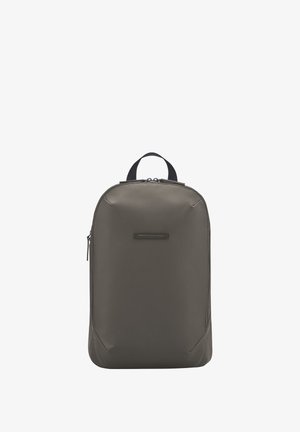Sac à dos gris foncé en matériau lisse et durable. Dispose d'une poignée supérieure et d'un compartiment principal zippé, avec des accents subtils et un design minimaliste.