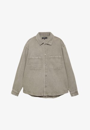 Stor lysebrun skjorte med knapper, to brystlommer og klassisk krave, lange ærmer og en let buet kant.