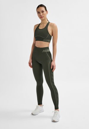 Ensemble athlétique vert olive avec texture côtelée. Le soutien-gorge de sport a un dos nageur ; les leggings taille haute ont des coutures contrastées et un logo.