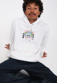Grijze hoodie met rode stiksel met een centraal ontwerp van een glimlachend gezicht omgeven door een wereldbol, twee figuren aan elke kant, en een voorkantzak.