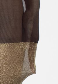 Przezroczysta brązowa bluzka z długim rękawem, z metaliczną złotą dolną częścią, ukazująca kontrast w teksturze i kolorze na jednolitym tle.