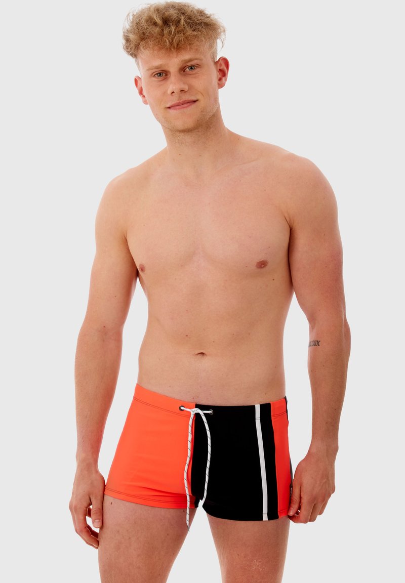Shorts de bain pour hommes avec un devant orange vif et un dos noir, ornés d'une bande blanche et d'une taille élastique avec cordon de serrage. Tissu lisse, conception ajustée.