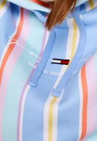 Sudadera de color azul claro con rayas verticales en naranja, rosa, amarillo y lavanda. Cuenta con una capucha con cordones y un detalle del logo bordado.