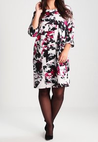 Luftiges Kleid in einem weißen, schwarzen und rosa abstrakten Muster; mittellange Ärmel; runder Ausschnitt; glattes Material; endet über dem Knie.