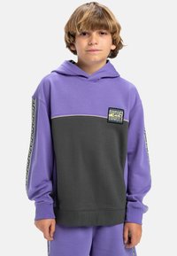 Hoodie violet et gris à manches longues, avec une poche avant, des détails rayés sur les manches et un patch logo sur la poitrine.