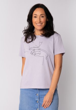 T-shirt à manches courtes lavande clair avec un design en art linéaire noir de mains et d'une feuille sur le devant. Tissu doux, coupe décontractée.