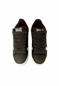 Sneakers in pelle marrone con accenti bianchi, dotate di lacci spessi, superficie testurizzata e design della punta arrotondata. Marchio visibile sulla linguetta.