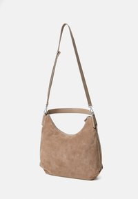 Tannfarbige Wildleder-Schultertasche mit geschwungener Form, akzentuiert durch einen flachen Ledergriff und silberne Beschläge, mit einem Reißverschlussverschluss und weicher Textur.