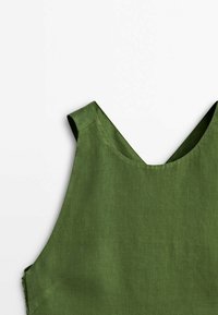 Haut en lin vert avec un décolleté en V et de larges bretelles. Texture lisse avec une légère brillance. Style minimaliste et lignes épurées.
