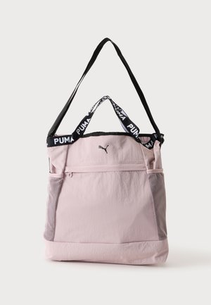 Hellrosa Puma Tote-Tasche mit schwarzem Schultergurt, kurzen Griffen mit Puma-Logo, vorderer Reißverschlusstasche und seitlichen Netzfächern.