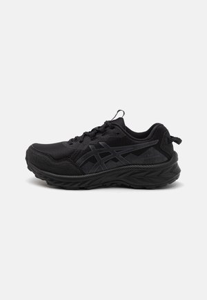 Baskets de sport noires avec semelle texturée, dessus en mesh, fermeture à lacets à l'avant et marquage discret à motif sur le côté.