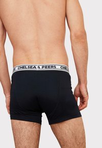 Svarta kalsonger för män med ett vitt elastiskt midjeband som har texten "CHELSEA PEERS". Tyget är slätt med en åtsittande design, vilket visar en nära passform.