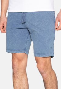 Siniset farkkushortsit, joissa on joustava vyötärö ja naru, kevyesti haalistunut pinta ja hienovarainen logo alahelmassa.