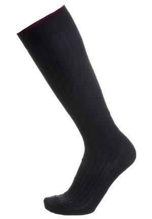 Calza nera fino al ginocchio con texture a coste e sottile bordo rosso nella parte superiore e nella punta, mostrata su uno sfondo bianco.