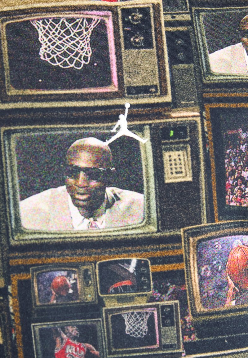 T-shirt avec imprimé intégral présentant des télévisions vintage avec des images de scènes de basket-ball et une figure centrale. Les couleurs incluent le noir, le beige et le rouge.