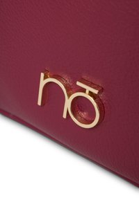 Borsa a tracolla fucsia in pelle con logo in tonalità oro, caratterizzata da una texture liscia e un design minimalista, che mette in risalto un'estetica moderna.