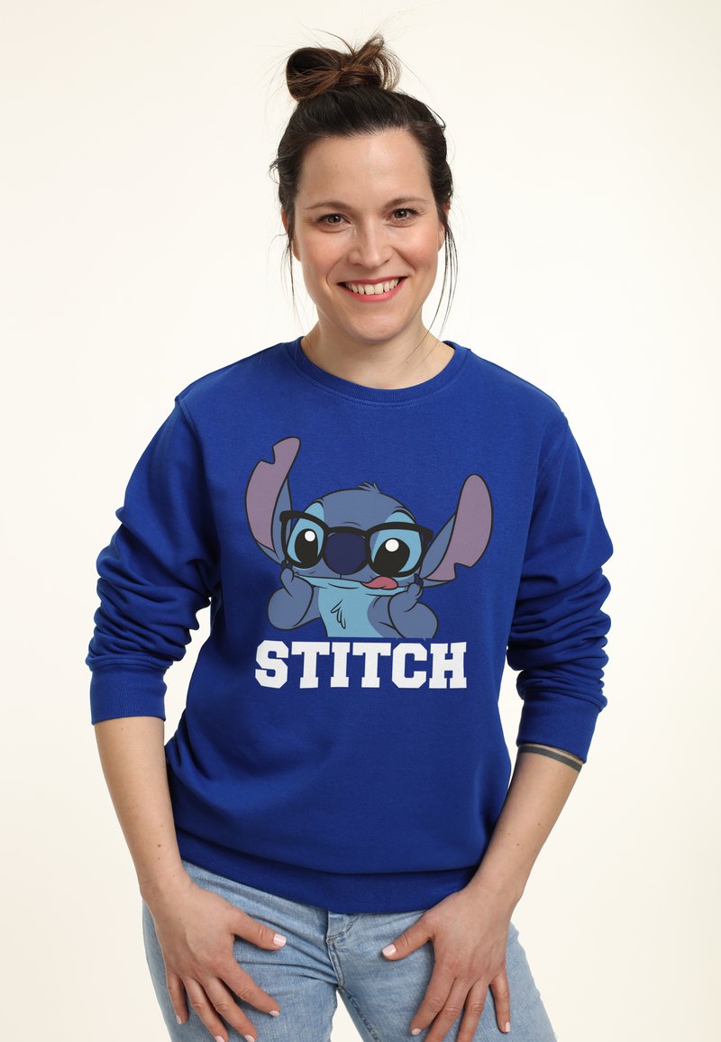 Blauer Pullover mit einem Cartoon-Charakter mit Brille, bedrucktem Text "STITCH" in Weiß. Mit gerippten Bündchen und lässigem Schnitt.