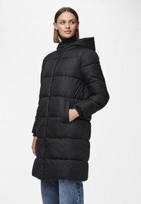 Giacca lunga nera imbottita con cappuccio, dotata di zip frontale, due tasche laterali, polsini a coste e texture trapuntata.