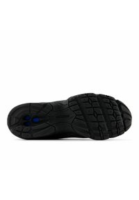 Svart yttersula på sportskor med texturerat gummi för grepp, med cirkulära mönster och blå accenter i häldelen för dämpning.