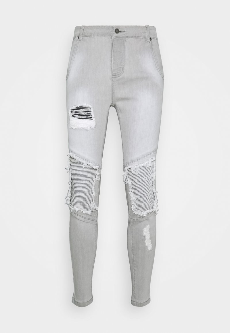 Světlé šedé skinny džíny s několika trhlinami a třepícími se okraji. Obsahují horizontální žebrovaný vzor na koleni. Vyrobeno z denimového materiálu.