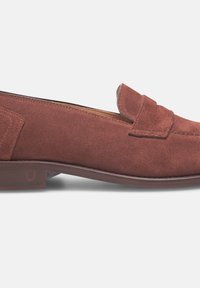 Mocassino in suede marrone con tacco piatto, caratterizzato da un dettaglio di sovrapposizione cucito sulla tomaia e una finitura liscia e opaca.