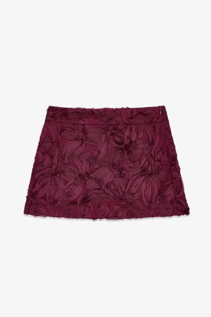 Burgundy fabric skirt with floral embroidery and textured detailing, featuring a straight silhouette and fringe hem.
