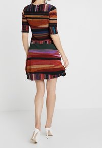 Abito aderente a maniche corte con strisce orizzontali multicolori in arancione, viola e verde, con gonna svasata e bordature nere.