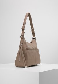 Borsa a spalla in pelle taupe con tracolla regolabile, tasche con zip frontale e laterale, esposta su un piedistallo bianco contro uno sfondo semplice.