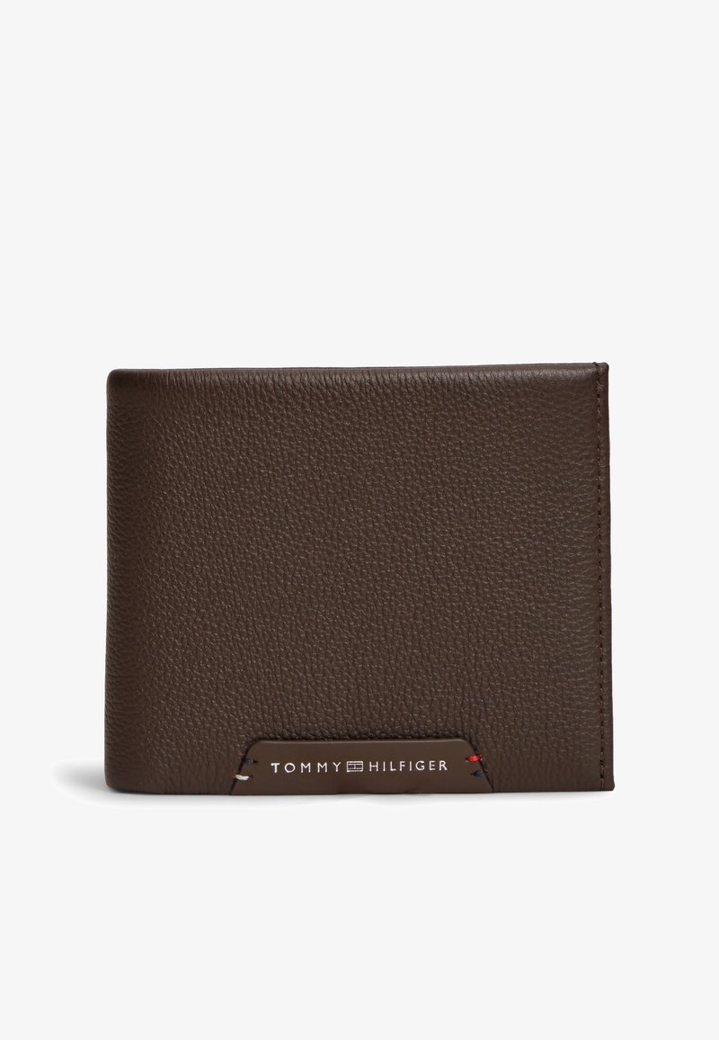 Portefeuille en cuir marron texturé avec un petit patch logo Tommy Hilfiger cousu, centré sur la partie inférieure avant.