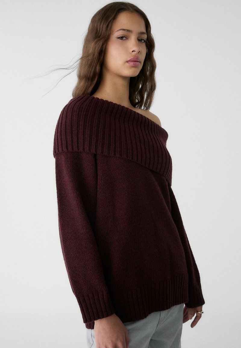 Bordo pulover z off-shoulder obliko, rebrastim ovratnikom in širokimi rokavi. Narejen iz strukturirane pletene tkanine.
