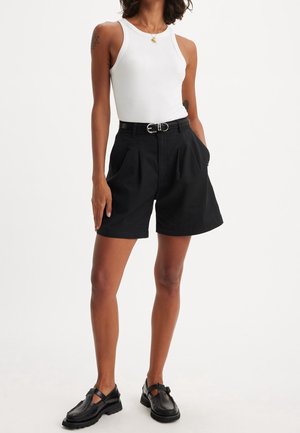 Černé plisované šortky s vysokým pasem a poutky na opasek, doplněné o přiléhavé bílé tílko. Hladká tkanina, neformální design, bez viditelných vzorů.