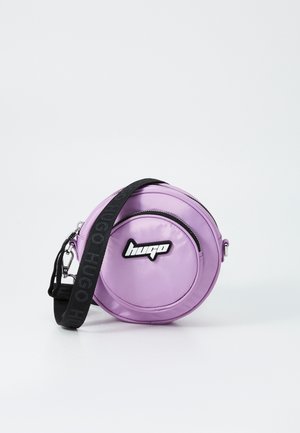 Round purple bag made of glossy material, featuring a black logo and strap with printed text. Zipper closure and smooth texture details.