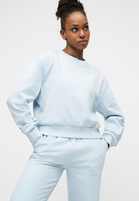 Ανοιχτό μπλε φούτερ με στρογγυλή λαιμόκοψη σε απαλό ύφασμα, με ριμπ μανσέτες και τελείωμα, συνδυασμένο με παντελόνι φόρμας σε ίδιο χρώμα με ελαστική μέση.