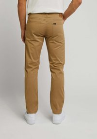 Khaki chino's met een rechte pijp, gemaakt van een katoenmengeling. Voorzien van twee achterzakken en een leren logopatch op de tailleband.