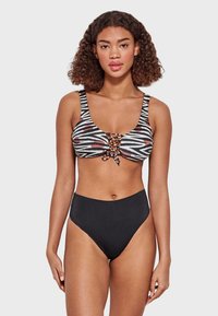 Bikini de dos piezas que presenta un sujetador de estampado de cebra en negro, blanco y rojo con un frente ajustable; parte inferior negra de cintura alta. Textura de tela suave.