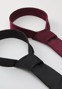 Deux cravates, une noire et une bordeaux, en tissu lisse, présentant un design classique avec un détail noué.