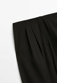 Pantalon noir sur mesure avec plis à l'avant et poche latérale fendue, présenté à plat sur fond blanc.