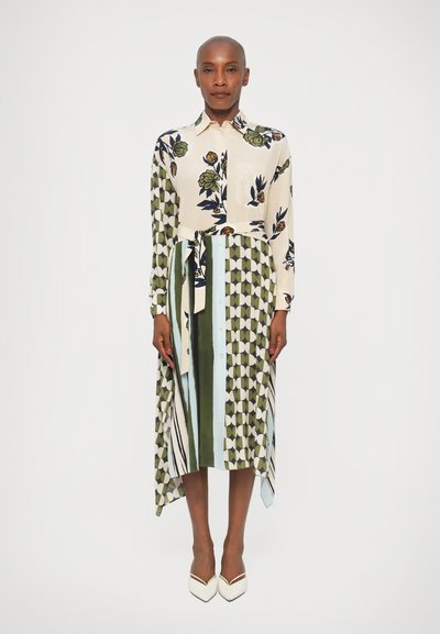 Robe à motifs floraux et géométriques avec une double longueur, des manches longues et une taille ceinturée. Les couleurs comprennent du crème, du vert et du bleu marine.