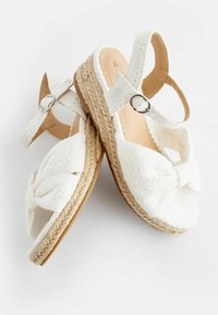 Sandali espadrilles bianchi con un dettaglio a fiocco testurizzato, suola intermedia in juta intrecciata e cinturino alla caviglia con una fibbia argentata.