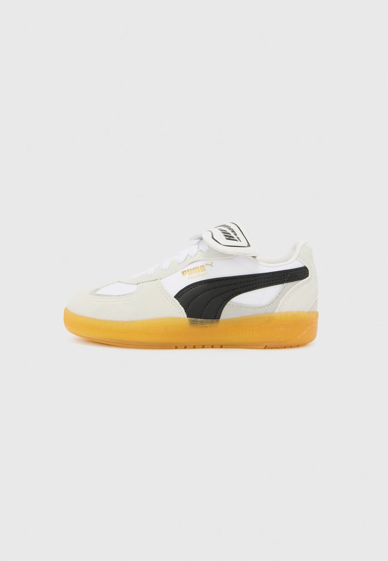 Tenisi Puma cu un căptușit din piele albă și gamă de nubuc, bandă de accent neagră și talpă din cauciuc galben. Design cu vârf rotund.