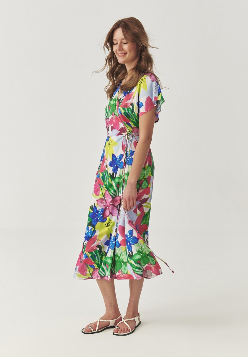 Bloemenpatroon jurk met korte mouwen, in levendige kleuren zoals roze, blauw en groen. Strikken in de taille, enkel-lange zoom.
